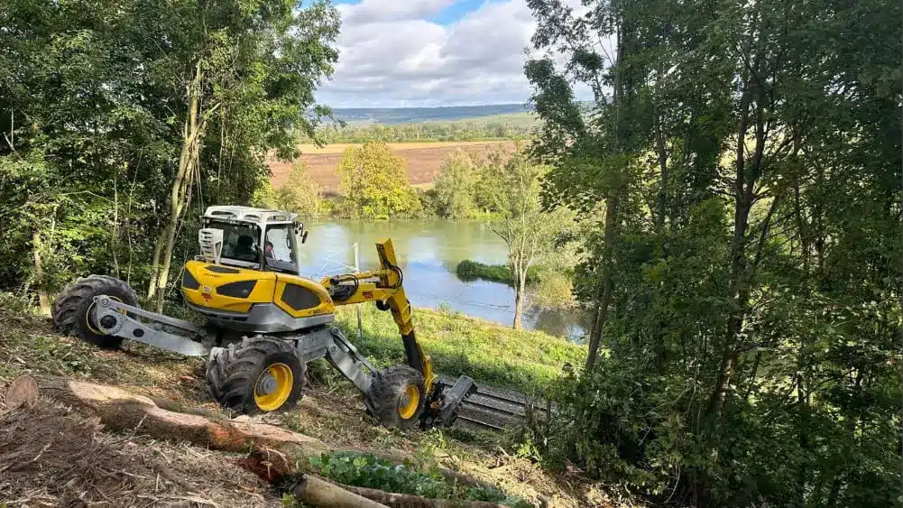Une machine jaune et noire travaille sur le bord d'une rivière.