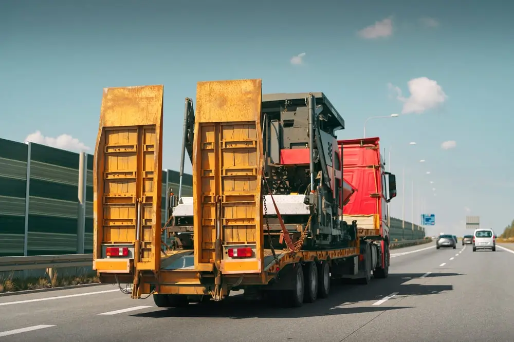 Camion de transport d'engins lourds sur une route très fréquentée.