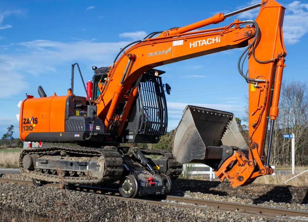 Une excavatrice ou une excavatrice de chemin de fer Kiwirail entretenant les titres de train sur la ligne principale jusqu'à la côte ouest.