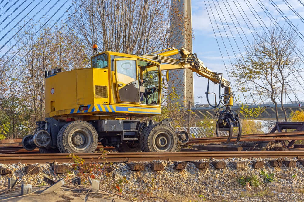 Enlèvement des anciennes traverses et voies ferrées à l'aide d'une pelle à fourches grappin.