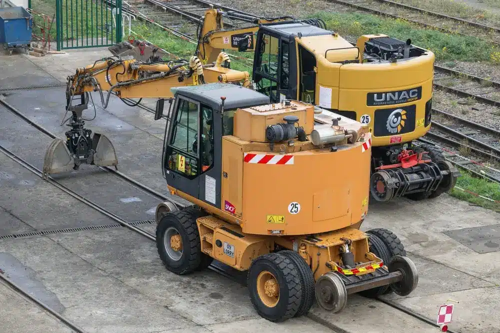 Vue sur une excavatrice sur roues orange, combinant route et rail.