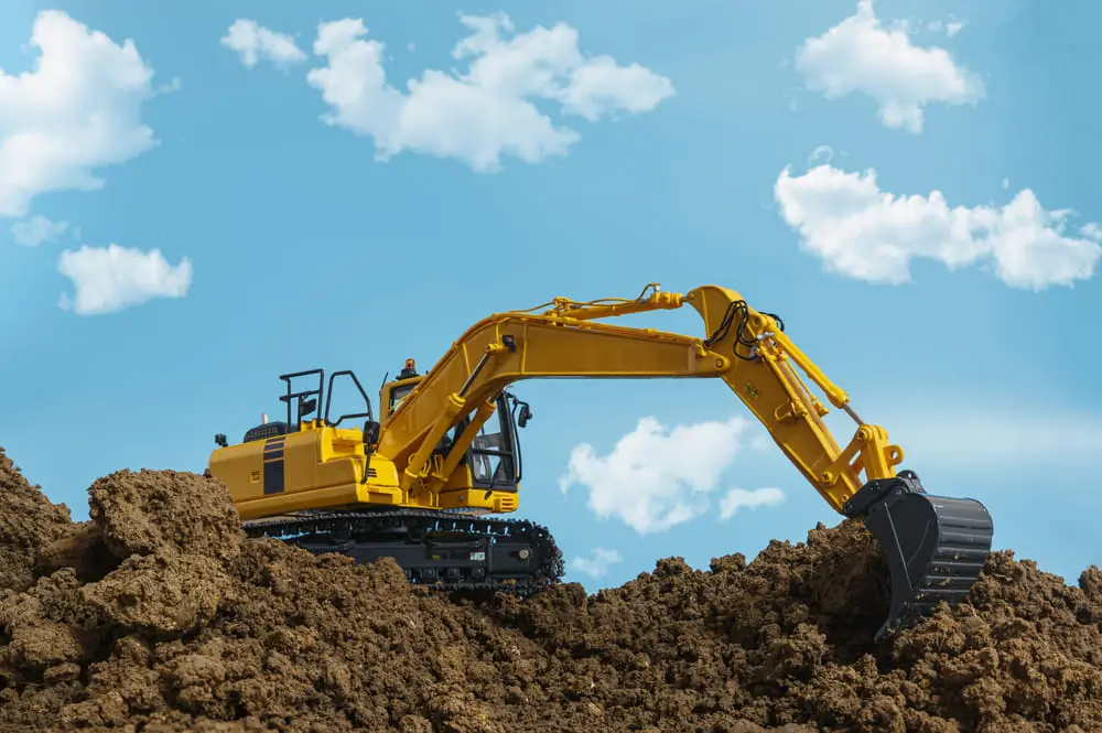 Des excavatrices jaunes creusent le sol sur le chantier, avec le ciel et les nuages ​​en arrière-plan.
