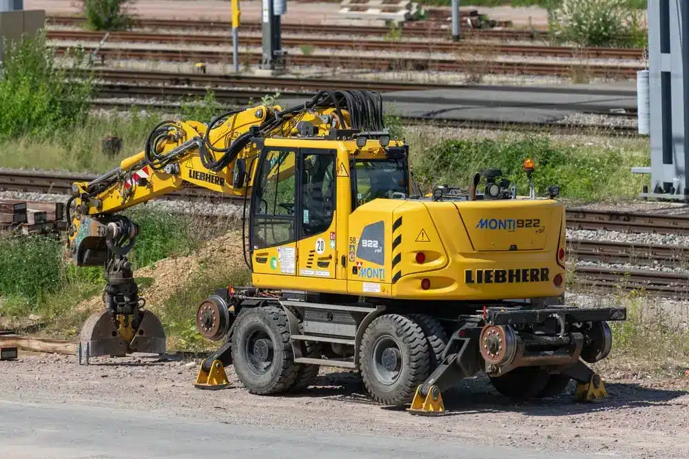 Vue d'une pelle sur roues Liebherr jaune, à la fois routière et ferroviaire.