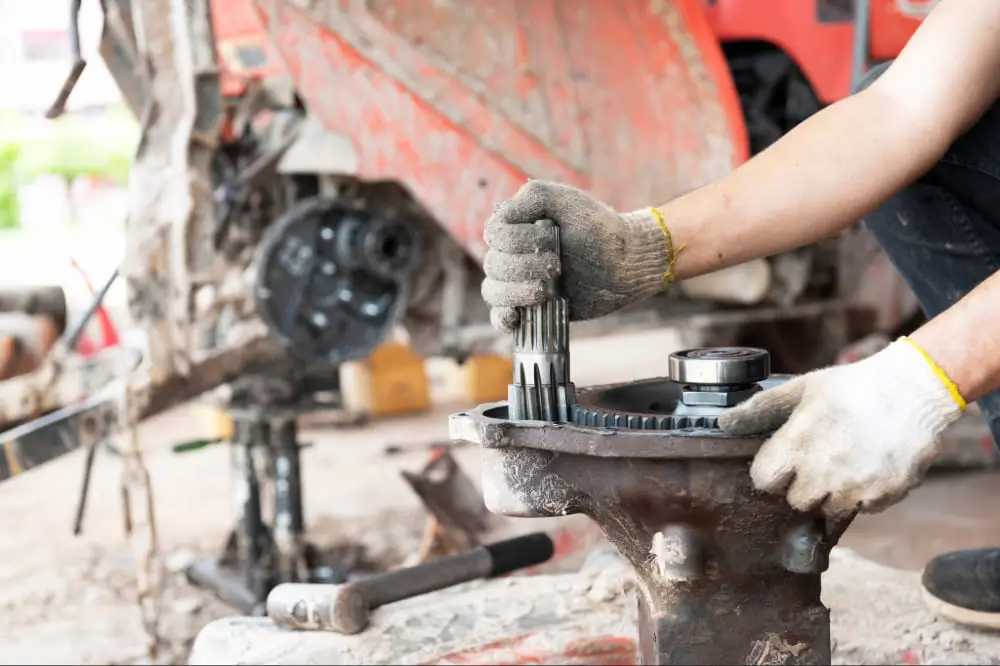 Un homme travaille sur une machine avec une clé à molette.