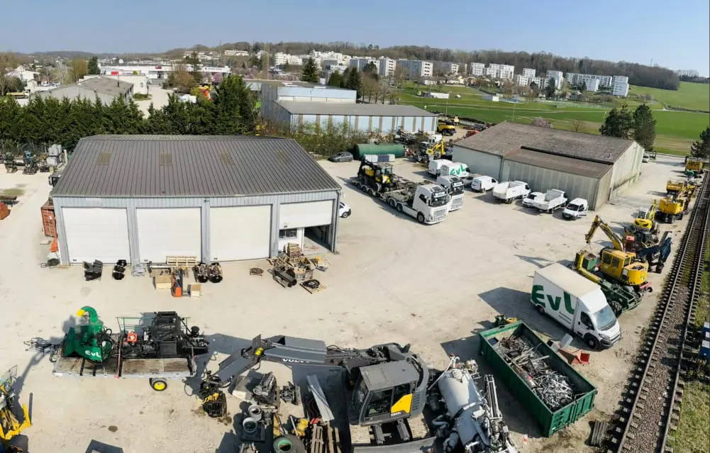 Vue aérienne d'un entrepôt avec plusieurs camions et équipements stationnés à l'extérieur.