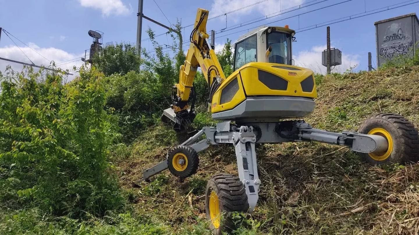Une machine jaune et noire sur une colline verdoyante, entourée de paysages naturels.